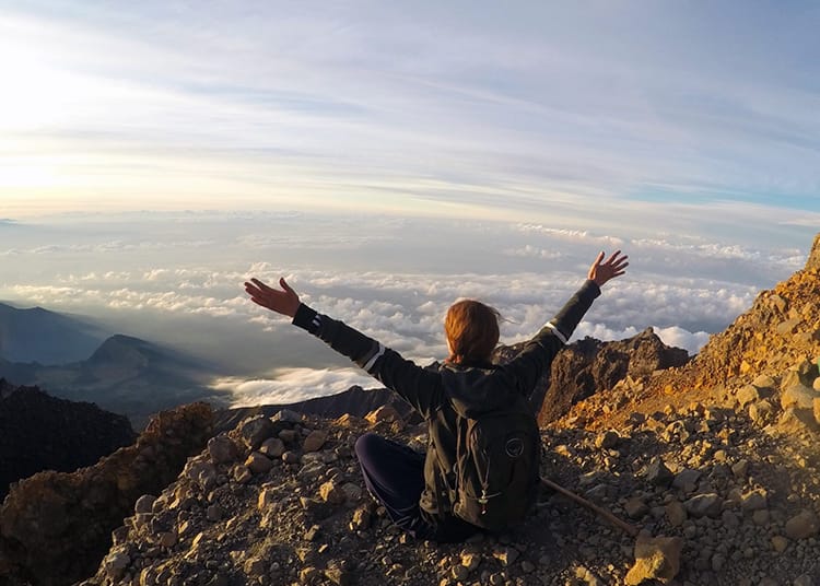 Michelle Della Giovanna from Full Time Explorer sits at the top of Mount Rinjani in Indonesia