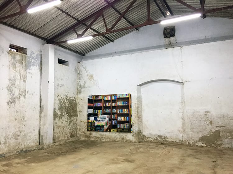An abandoned room with a mural of a book shelf painted on the wall in Fort Cochin