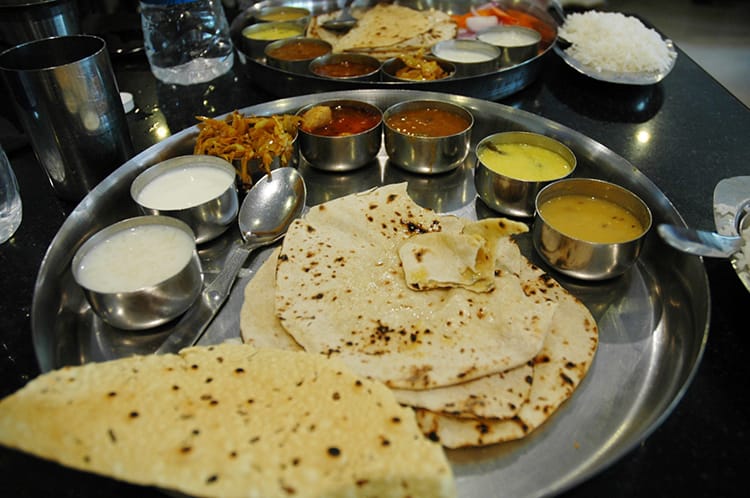 A traditional Thali set with several curries, dal, and naan