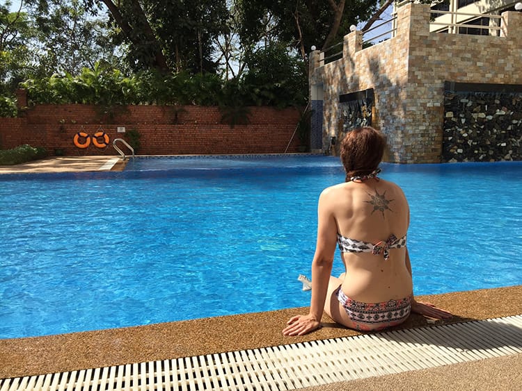 Michelle Della Giovanna from Full Time Explorer sits by a pool with a Sak Yant Tattoo on her back
