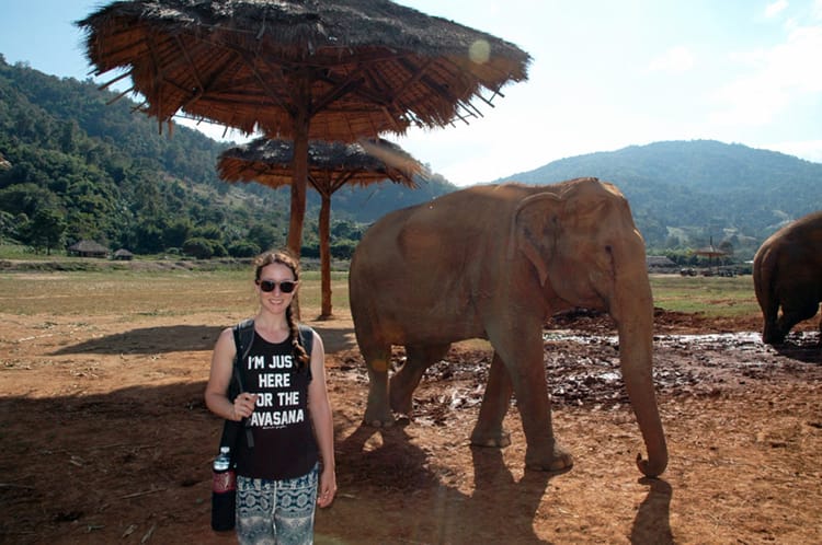 Michelle Della Giovanna from Full Time Explorer stands in front of a rescued elephant at Elephant Nature Park in Thailand