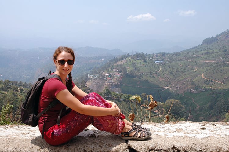 Michelle Della Giovanna from Full Time Explorer sits at the photo point in Munnar where tea plantations are in the background