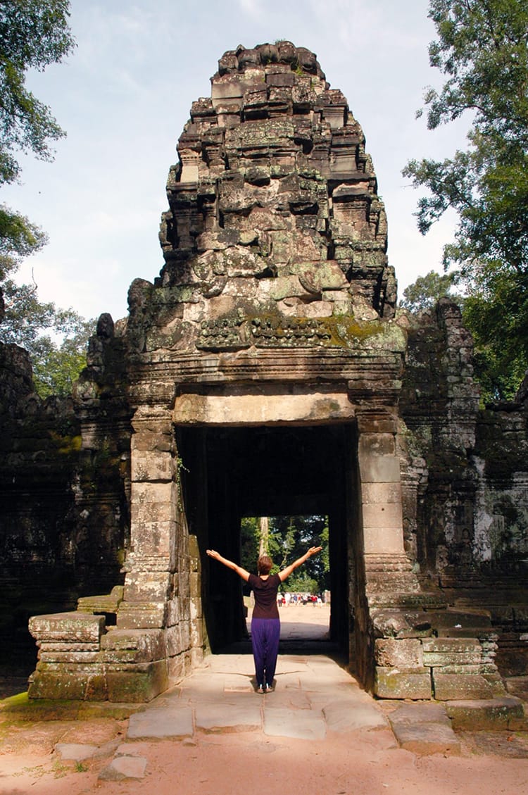 Michelle Della Giovanna from Full Time Explorer stands in front of one of the stone carved entry ways to a temple