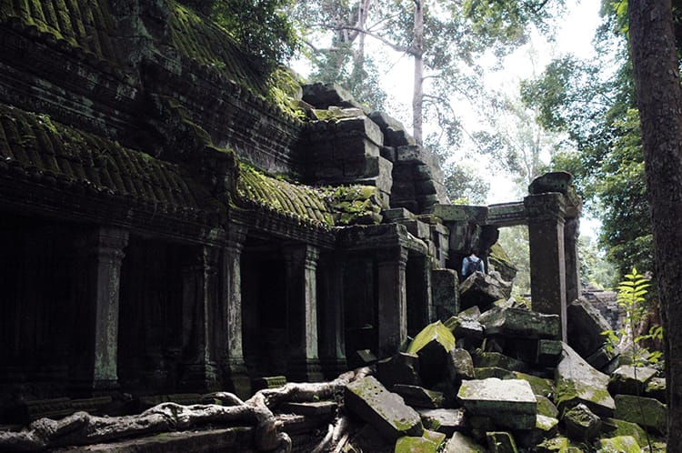 Moss and tree roots grow over an abandoned temple in Angkor Wat