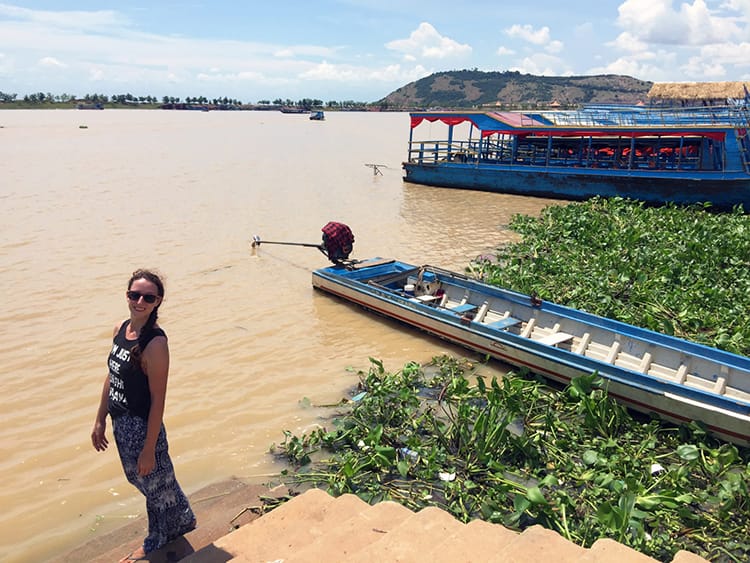 Michelle Della Giovanna from Full Time Explorer stands on the edge of a mucky Tonle Sap Lake in Siem Reap, Cambodia