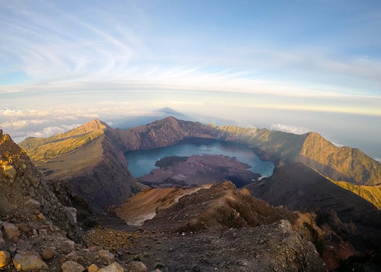 The view of the crater lake below at sunrise with spectacular colors as the sun hits it