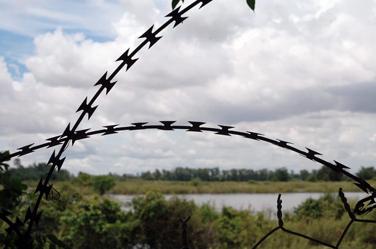A piece of barbed wire sticks out over a fence at the Killing Fields in Phnom Penh, Cambodia