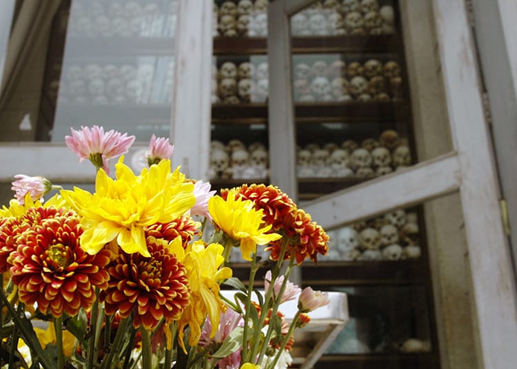 Bright flowers sit in front of a building holding bones found in the Killing Fields in Phnom Penh, Cambodia