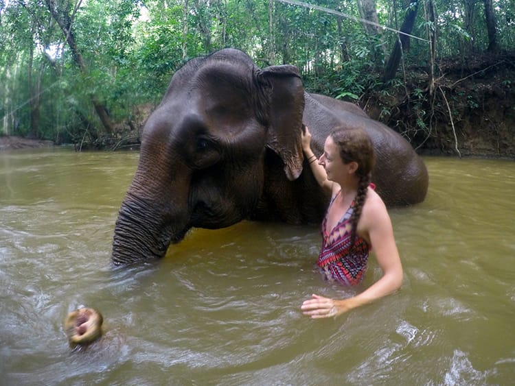 Michelle Della Giovanna from Full Time Explorer stands in a river with an elephant at the Mondulkiri Elephant Sanctuary