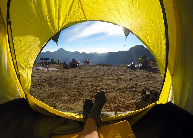 Michelle Della Giovanna from Full Time Explorer sticks her feet out of a bright yellow tent at camp 1