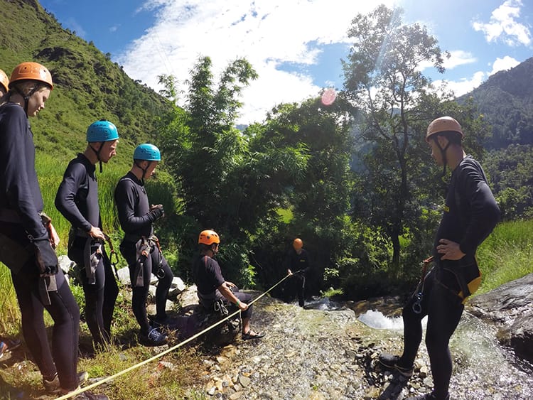 A guide shows the group how to properly abseil a waterfall as the first person heads down