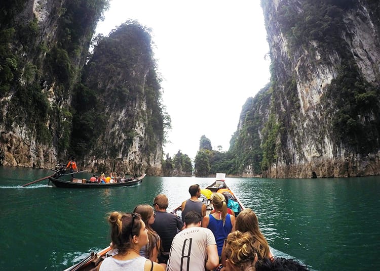 A boat in Khao Sok National Park floats through tall limestone mountains