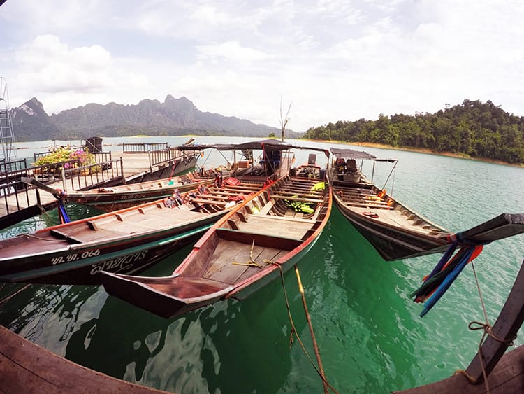 Three longboats line up in Khao Sok National Park on the bright teal water