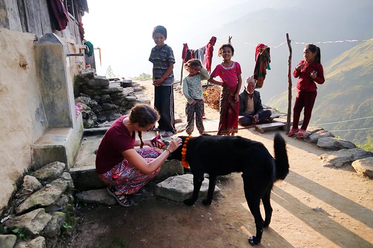 Michelle Della Giovanna from Full Time Explorer puts a mala marigold flower garland around the neck of a dog
