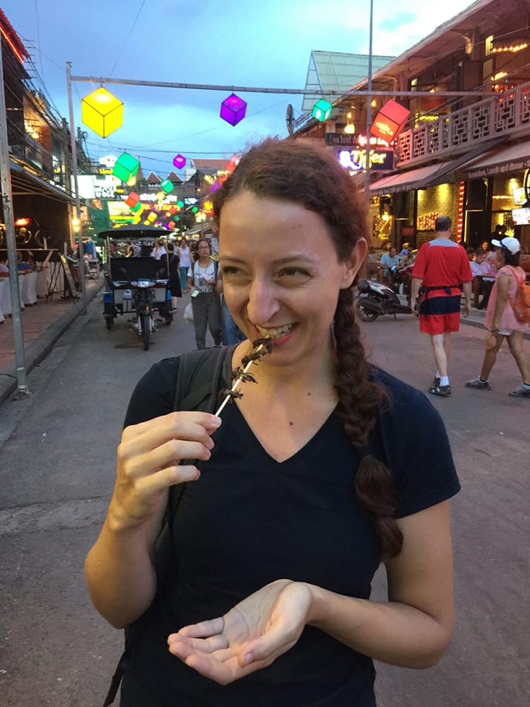 Michelle Della Giovanna from Full Time Explorer eats crickets on the street in Cambodia