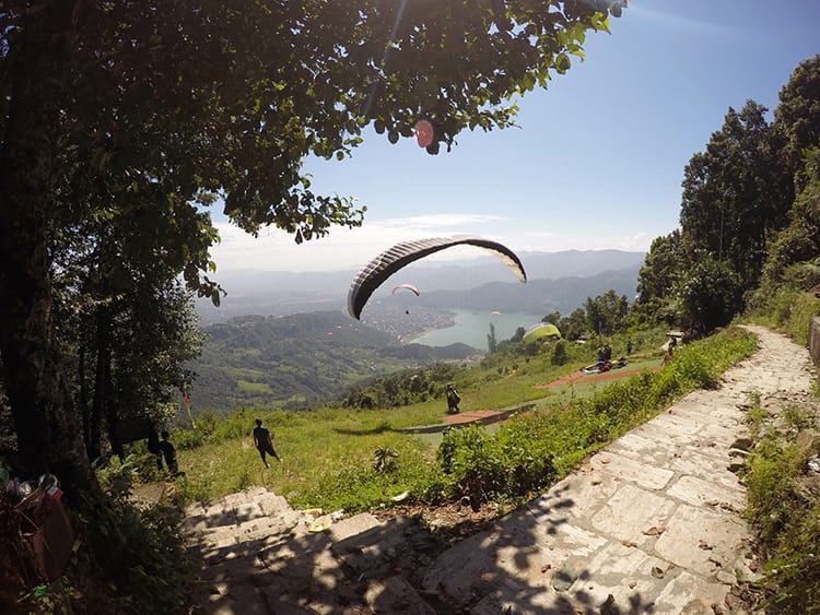 Paragliders take off from the top of a hill in Pokhara, Nepal