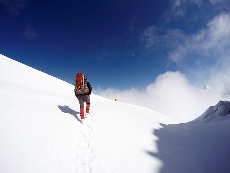 A Sherpa guide walks up a snow covered mountain on the way to Mera Peak