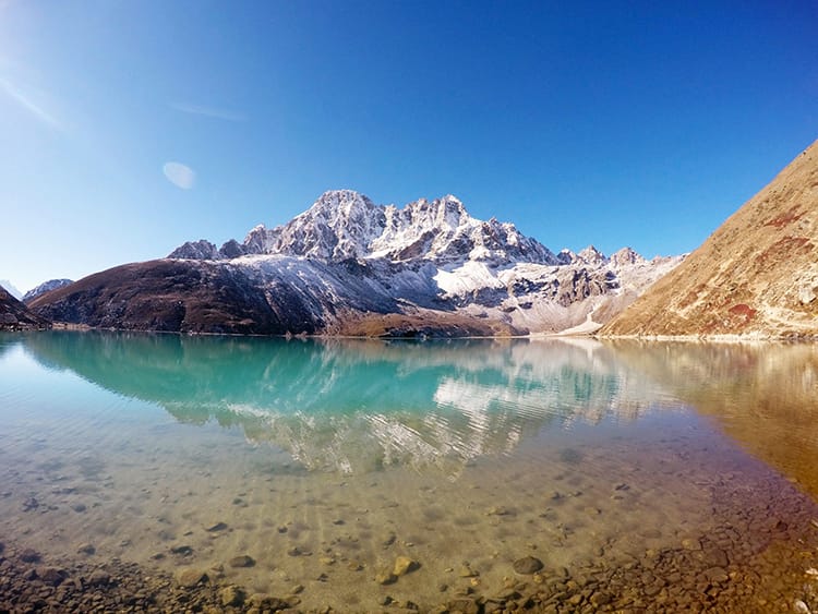 A stunning view of the Himalaya reflected in the turquoise water of Gokyo Lake on a clear day