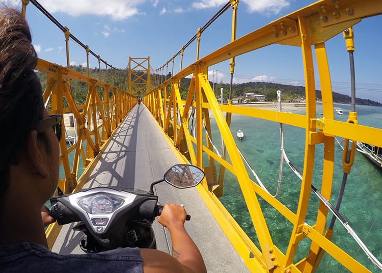 A scooter crosses the yellow bridge in Bali