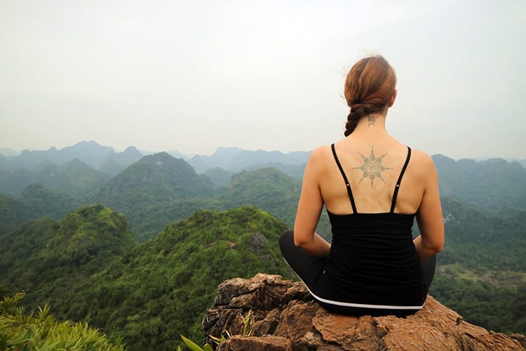 Michelle Della Giovanna from Full Time Explorer sits on a rock after hiking up Ngu Lam Peak in Cat Ba National Park