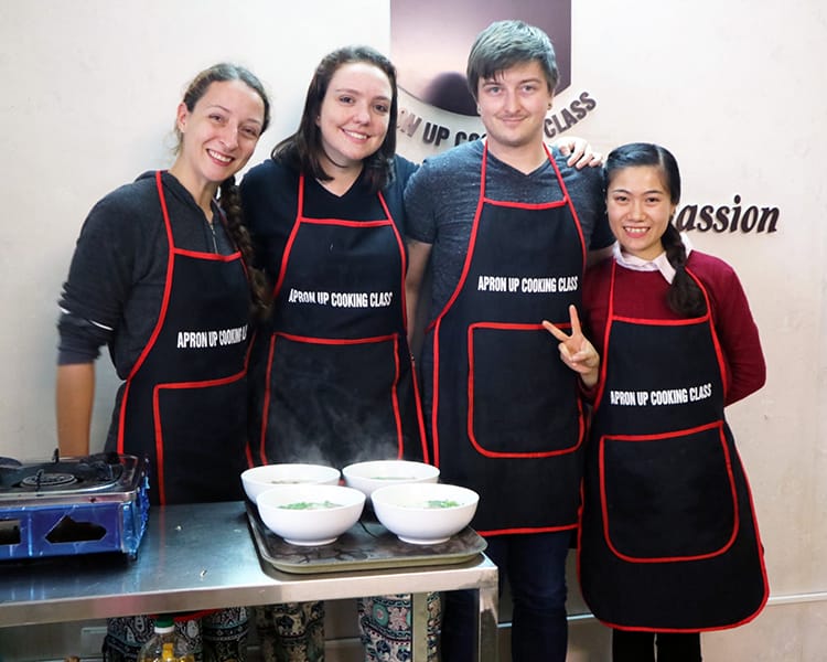 Michelle Della Giovanna from Full Time Explorer and friends wear aprons at a cooking class in Vietnam