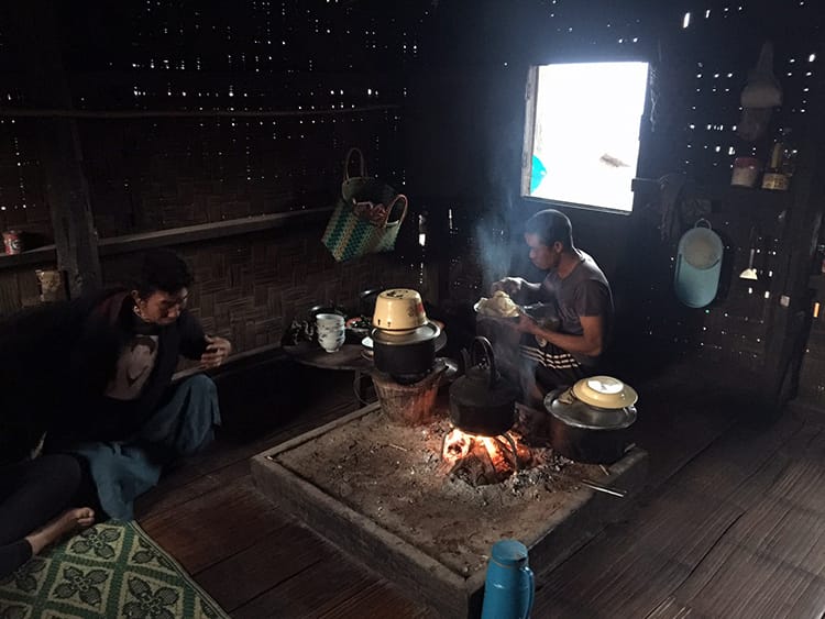 Locals sit inside a local home cooking over an open fire