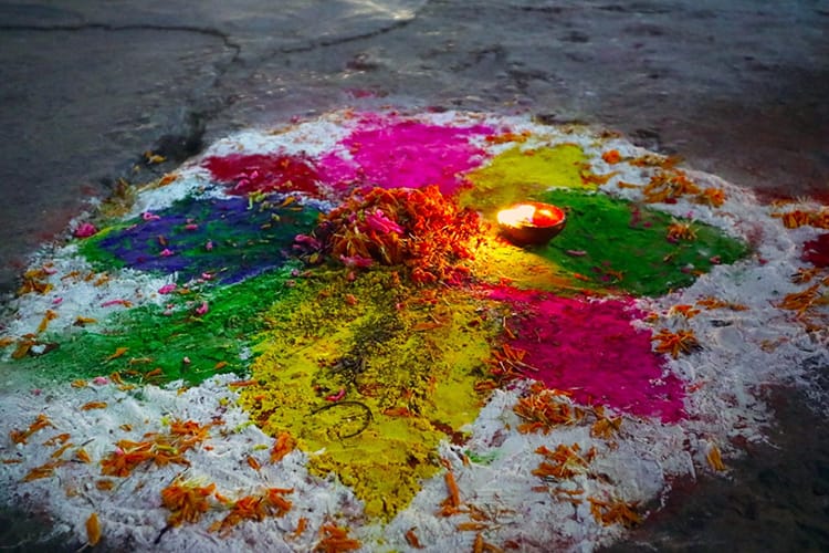 A brightly colored mandala made out of powder in front of a door in Nepal during Tihar
