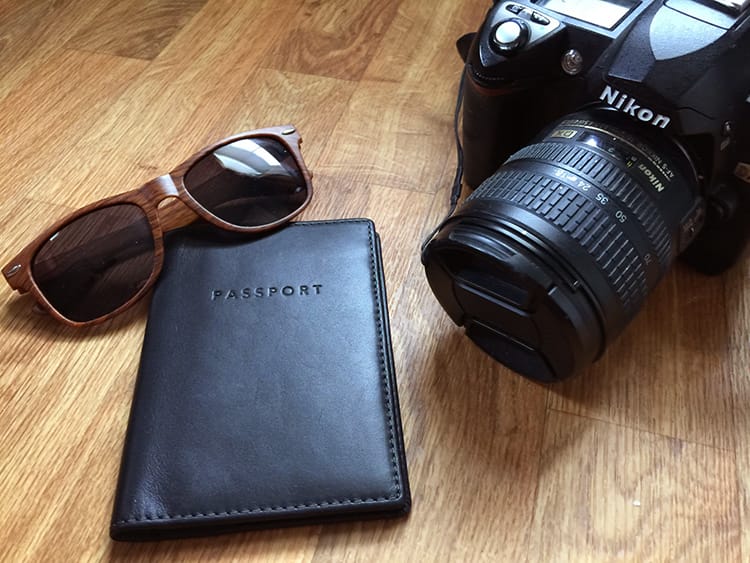 A passport, sunglasses, and a DSLR camera