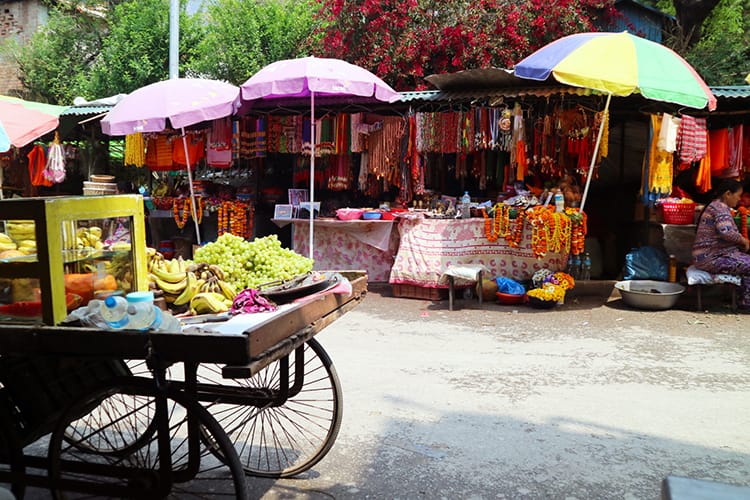 Small stands with umbrellas sell marigolds and fruits nearby a temple in Nepal