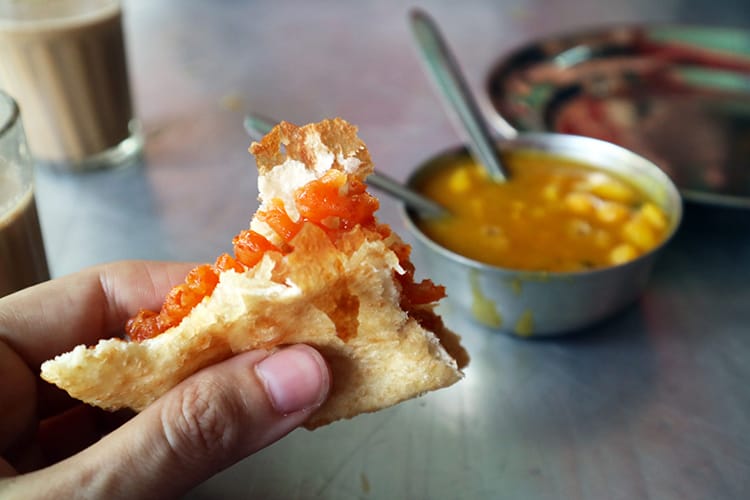 A jeri sweet inside a piece of puri dipped into chickpea curry