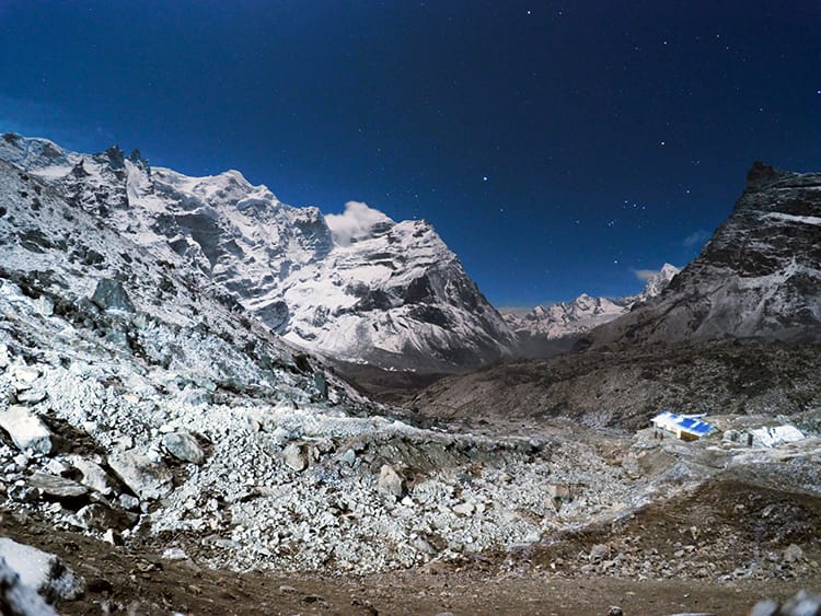 A night time view of a small village along the Mera Peak trek with the mountains and stars glowing brightly in the dark