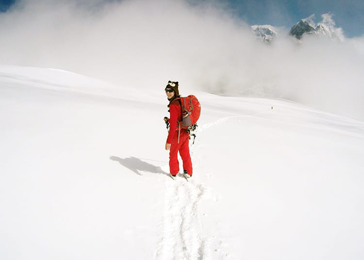 Michelle Della Giovanna from Full Time Explorer poses for a photo on the way to Mera Peak after a snowstorm left a fresh coat of white snow covering the mountain
