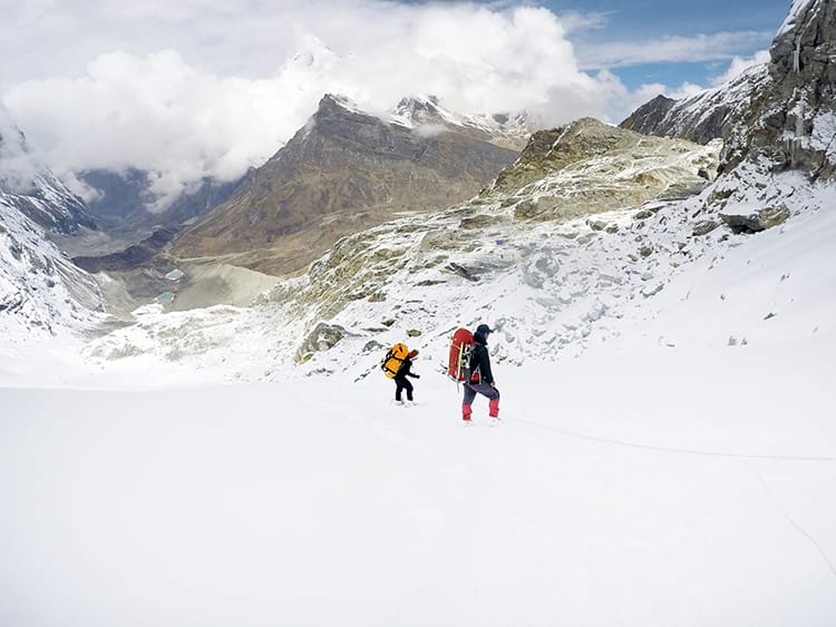 A guide helps a porter carrying gear up a fixed rope on the way to Mera Peak in Nepal