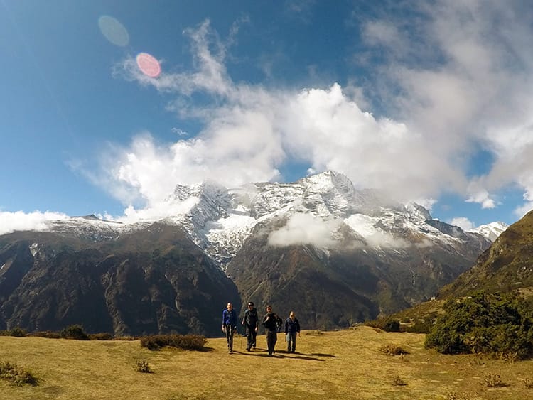 Four hikers walk over a large field in the middle of the Himalayas