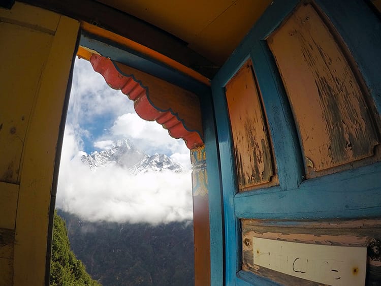 A brightly painted doorway sits open with the most magnificent view of the Himalayas on the other side