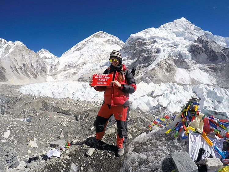 Michelle Della Giovanna from Full Time Explorer holds the Everest Base Camp sign while standing on the glacier at Base Camp