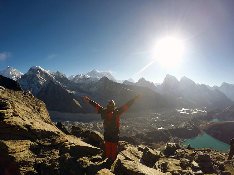 Michelle Della Giovanna from Full Time Explorer holds her hands up in the air in excitement at the top of Gokyo Ri