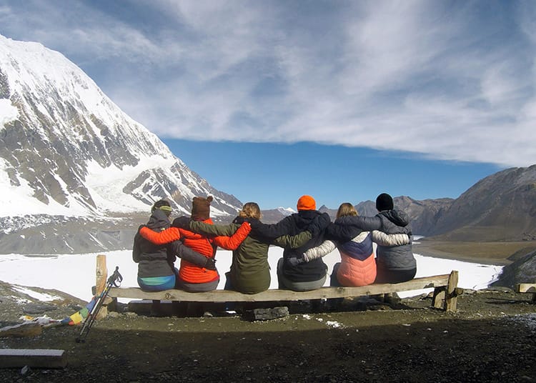 Michelle Della Giovanna from Full Time Explorer and five friends sit in front of Tilicho Lake on the Annapurna Circuit in Nepal
