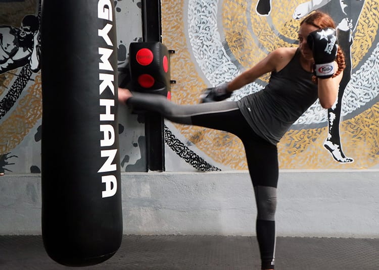 Michelle Della Giovanna from Full Time Explorer practices muay thai kicks on a heavy weight bag in Nepal