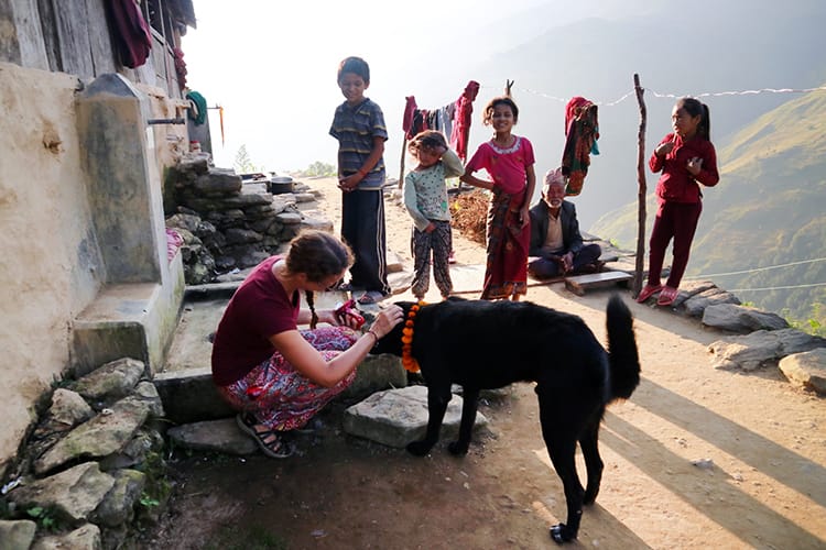Michelle Della Giovanna from Full Time Explorer puts a flower garland on a dog during the Tihar Festival in Nepal