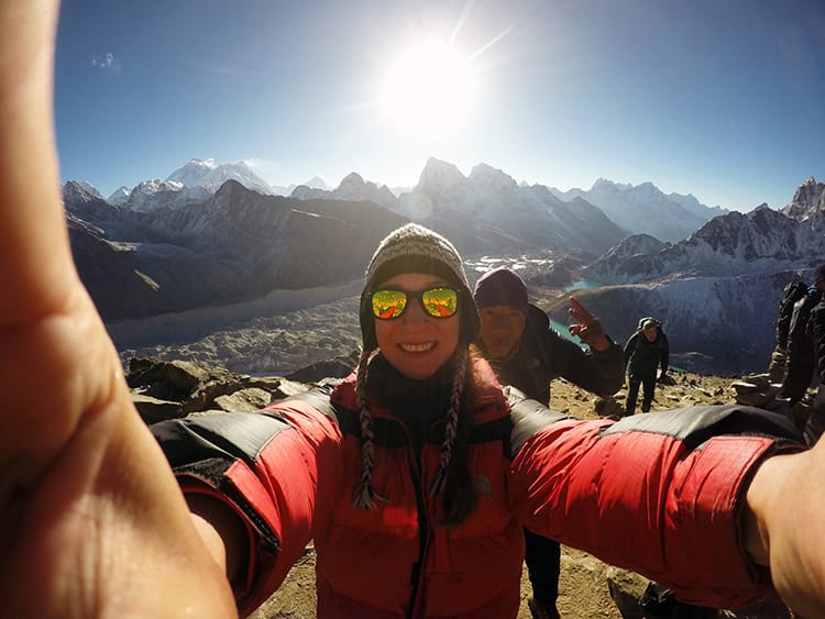 Michelle Della Giovanna from Full Time Explorer takes a selfie with her guide while bundled up in layers on the way to EBC