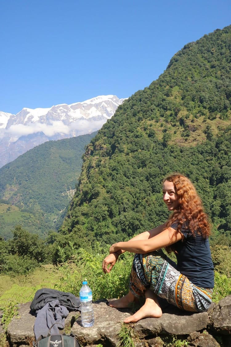 Michelle Della Giovanna from Full Time Explorer sits in front of the Himalaya mountains in Tangting Village