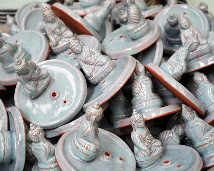 Buddha statues that have been glazed blue sit in a pile waiting to be shipped