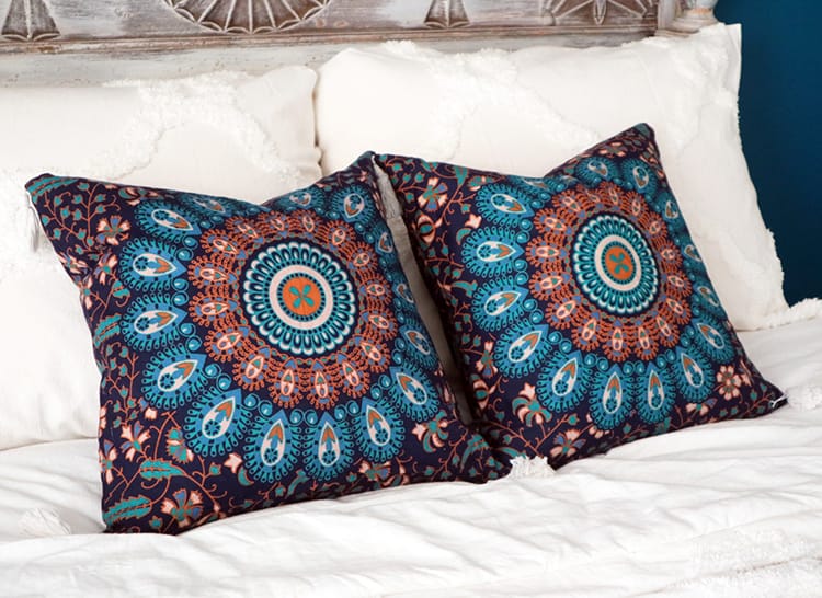 Two dark blue pillows with a teal and tan mandala design on them from Nepal
