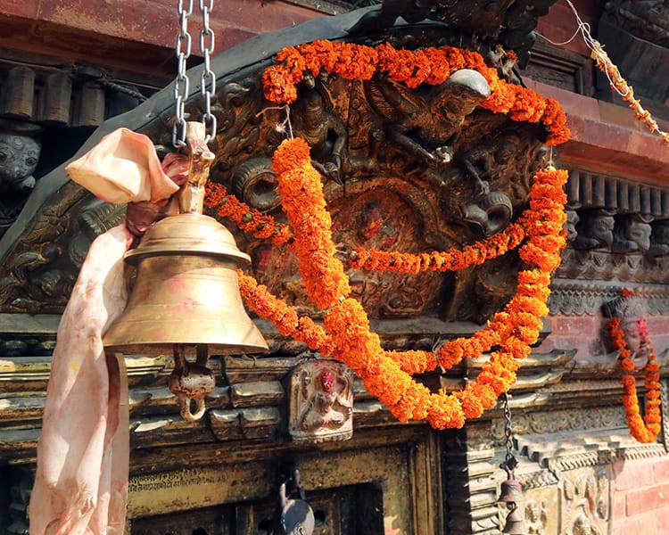 A marigold garland draped over the wood carving above the door to Changu Narayan Temple