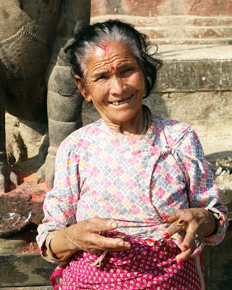 A woman sells flowers in front of Changu Narayan with a smile
