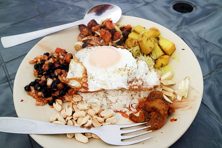 A Newari platter with chicken, beans, an egg, potato, and beaten rice