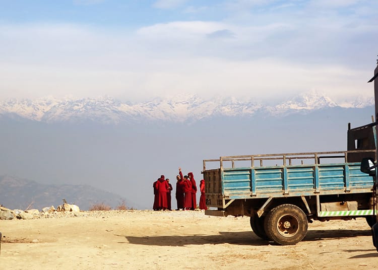 A group of monks stand in front of the mountain view taking photos