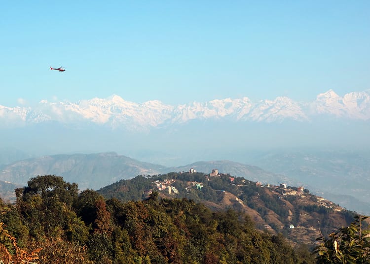 A helicopter flies to Nagarkot in front of the Himalayas
