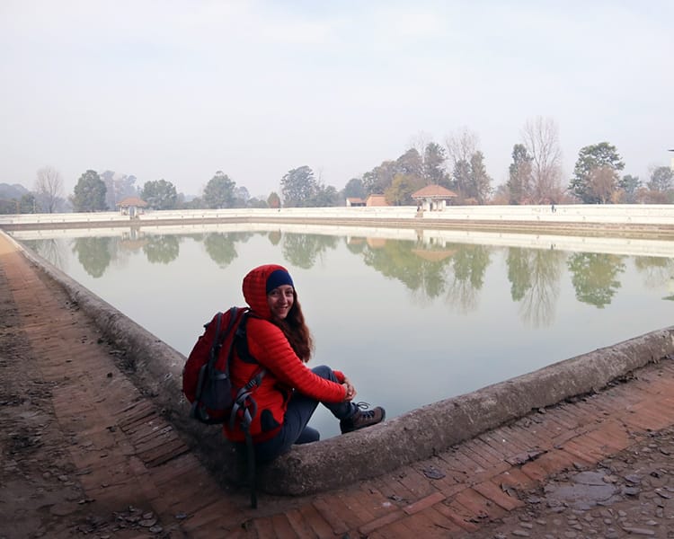 Michelle Della Giovanna of Full Time Explorer sits on the edge of Siddha Pokhari in Bhaktapur